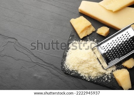 Whole and grated parmesan cheese on black table, flat lay. Space for text