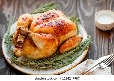 Whole Grill Chicken With Caramelized Skin And Fresh Rosemary On A Wooden Dinner Table.