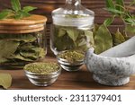 Whole and ground aromatic bay leaves on wooden table