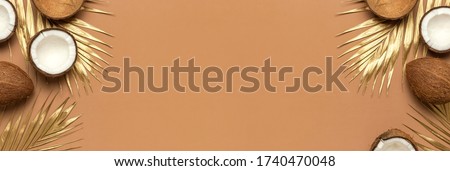 Whole and half coconut, golden palm leaf on brown background. Creative layout with coconuts. Minimal flat lay style, top view copy space. Food concept. Tropical exotic fruit, summer background 