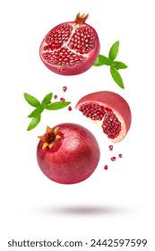 Whole and half fresh red pomegranate with seeds and green leaves flying in the air isolated on white background.