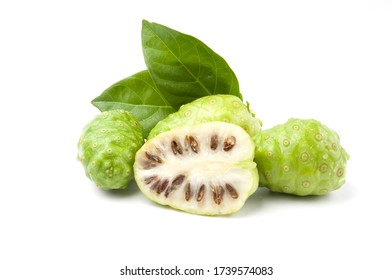 Whole and half of Noni or Morinda Citrifolia fruits with green leaf isolated on white background.