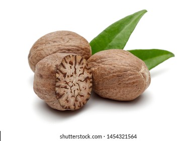 Whole and half nutmeg with leaves isolated on white background