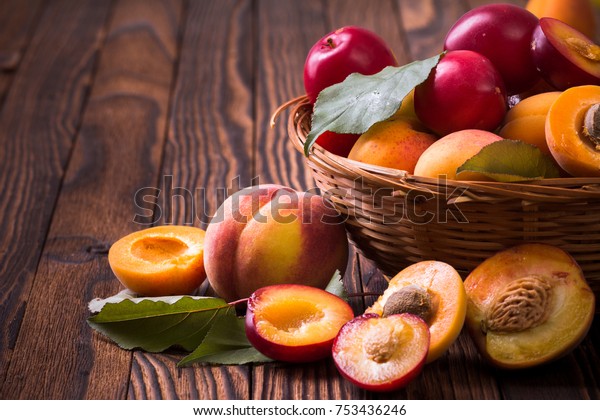 Whole\
and half peaches, plums and apricots in a\
basket