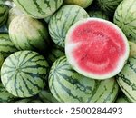 Whole and half sliced watermelons as background. Tropical fruit that is rich in water content, sweet and fresh. There are watermelons without seeds and watermelons with seeds.