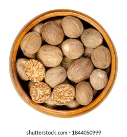 Whole and halved nutmegs in a wooden bowl. Fragrant or true nutmegs, dried seeds of Myristica fragrans, used as spice and in traditional medicine. Close-up from above, isolated over white. Food photo. - Powered by Shutterstock