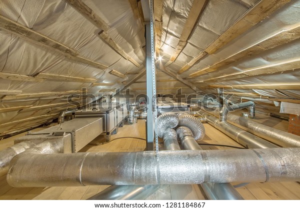 Whole house air\
ventilation and cleaning system. Ventilation pipes in silver\
insulation material on the\
attic
