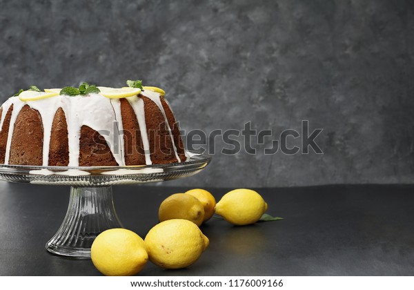 Whole lemon cream cheese bundt\
cake with slices of fresh lemons and mint on top. Extreme shallow\
depth of field with selective focus on cake. Free space for\
text.