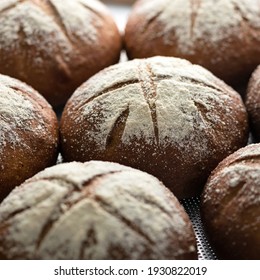 Whole loaves of dark bread in rows. Bread background. Close up. Fresh baked whole grain bread. Selective focus in the center. Food concept. Square format or 1x1 for posting on social media.