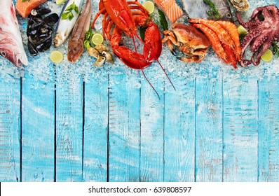 Whole lobster with seafood, crab, mussels, prawns, fish, salmon steak, mackerel and other shells served on crushed ice and wooden table