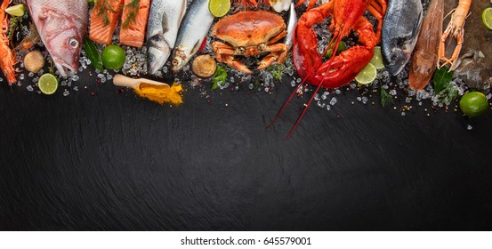 Whole lobster with seafood, crab, mussels, prawns, fish, salmon steak, mackerel and other shells served on black slate stone