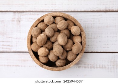 Whole nutmegs in bowl on light wooden table, top view - Powered by Shutterstock