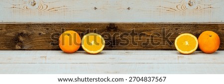 Whole orange and half orange in mirror composition on wooden background