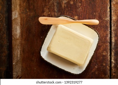 Whole Pat Of Farm Fresh Creamy Butter On A Small Rectangular Butter Dish With Wooden Spreader Or Knife Viewed Top Down On A Rustic Wood Table