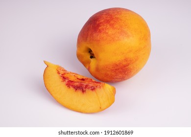 A Whole Peach And One Wedge Next To It