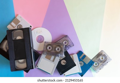 Whole plane, background depicting elements of the 1990s.Coloured cardboard creating triangular shapes and electronic storage devices, floppy disks, VHS tapes, cassettes and CD.