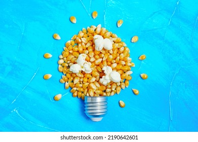 Whole And Popped Corn Kernels Arranged Into A Lightbulb Shape On Blue