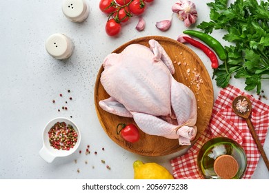 Whole raw chicken with ingredients for making rose pepper, lemon, thyme, garlic, cherry tomato, sorrel and salt in the kitchen on light grey slate stone or concrete background Top view with copy spac - Shutterstock ID 2056975238