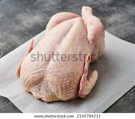 Whole raw chicken on white paper. Preparing raw chicken.