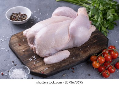 Whole Raw Chicken On A Wooden Board.