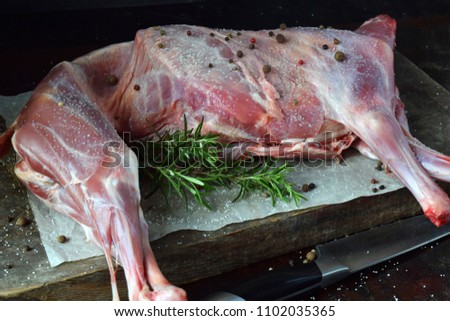 Whole raw lamb and knife on the wooden board. Sheep carcass with fresh herbs, spices. Raw meat. Free space for text.