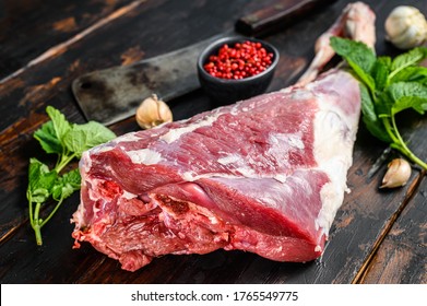 Whole raw leg of lamb. Fresh organic meat. Dark wooden background. Top view