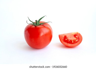 A whole red tomato and slice isolated on a white background