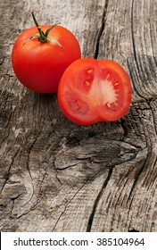 Whole red tomato with slice of tomato on wooden background close-up. Top view with copy space