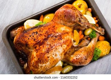 Whole roasted turkey with apples, pumpkin, potatoes, carrots and greens in baking dish - Shutterstock ID 1160332252