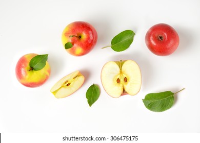 whole and sliced apples with leaves on white background