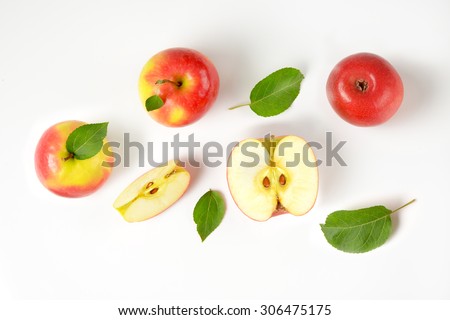 whole and sliced apples with leaves on white background