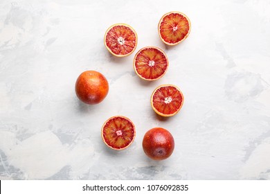 Whole and sliced bloody oranges on a light gray surface. Top view. Copy space.