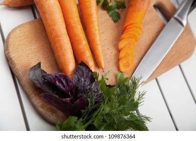 Whole and sliced fresh carrots on a cutting board.