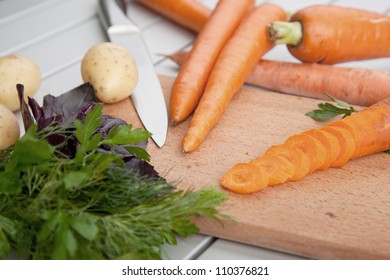 Whole and sliced fresh carrots on a cutting board.