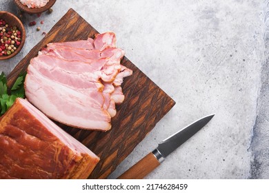 Whole Smoked Slab Bacon. Brisket. Sliced Smoked Gammon On A Wooden Table With Rosemary, Parsley, Pepper, Salt, And Garlic On Old Gray Concrete Table Background. Copy Space.