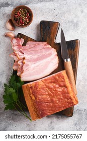 Whole Smoked Slab Bacon. Brisket. Sliced Smoked Gammon On A Wooden Table With Rosemary, Parsley, Pepper, Salt, And Garlic On Old Gray Concrete Table Background. Copy Space.