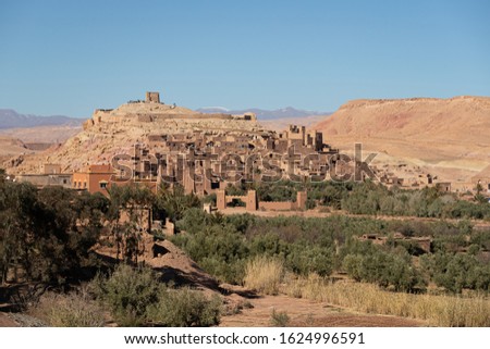 The whole UNESCO World Heritage Site of Ait Beb Haddou seen from the village on the other side of the river. The mud brick fortified town known as a kasbah is shown in beautiful late afternoon light 