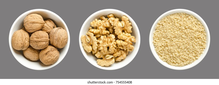 Whole, walnuts, kernel halves and ground walnuts in white bowls on gray background. Seeds of the common walnut tree Juglans regia, used as snack or for baking.  Macro food photo close up from above.