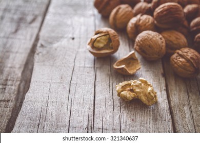 Whole walnuts with shell on rustic wood background, toned