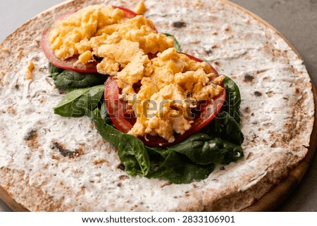 Whole Wheat Breakfast Wrap Assembly with Cream Cheese, Spinach, Tomatoes, and Scrambled Eggs