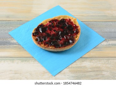 Whole Wheat English Muffin With Black Currant Jelly Preserves On Blue Napkin On Table