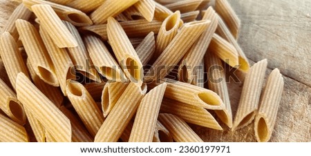 Whole wheat penne pasta, ready to be cooked. Healthy and nutritious food. Pasta, a typical dish of traditional Italian cuisine, in the whole wheat flour version.