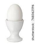 Whole white egg in a ceramic egg-cup, isolated on white background. Breakfast food.