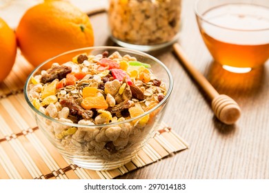 Wholegrain Cereals With Candied Fruits, Nut, Raisins, Oranges And Honey In Glass Plate On Wooden Background.