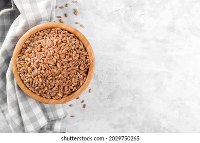 Wholegrain Uncooked Raw Spelt Farro In Wooden Bowl On Grey Stone Table Background, Food Cereal Background, View From Above, Copy Space