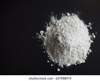 Wholemeal flour in a pile on isolated on black wooden table