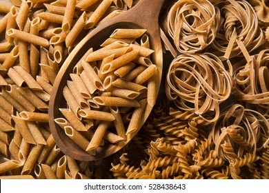 Wholemeal Fusilli into a spoon. Integral Pasta over a wooden table