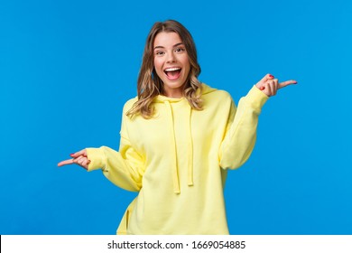 Why Not Try Both. Carefree Happy Smiling Young Blond Girl Suggest Two Variants, Pointing Fingers Left And Right As Dancing And Looking Camera Cheerful, Introduce Products, Blue Background