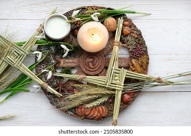 Wiccan altar for Imbolc sabbath. winter-spring pagan festive ritual. Brigid's cross, milk, candle, wheel of the year, snowdrops on wooden table. symbol of Imbolc holiday, spring equinox. top view