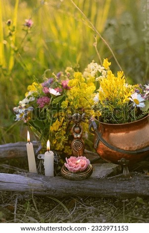 wiccan Goddess Candlestick, Copper witch cauldron with flowers, magic things, candles on meadow, abstract natural background. herb lore, occult. esoteric ritual, witchcraft, spiritual practice.